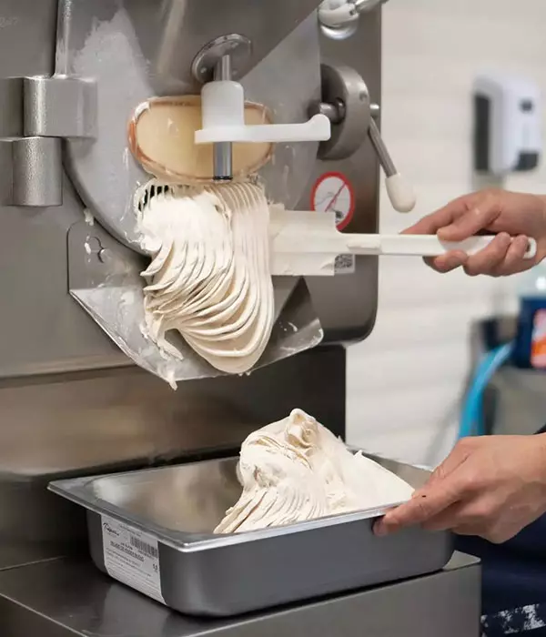 Heladero preparando helado cremoso en máquina profesional